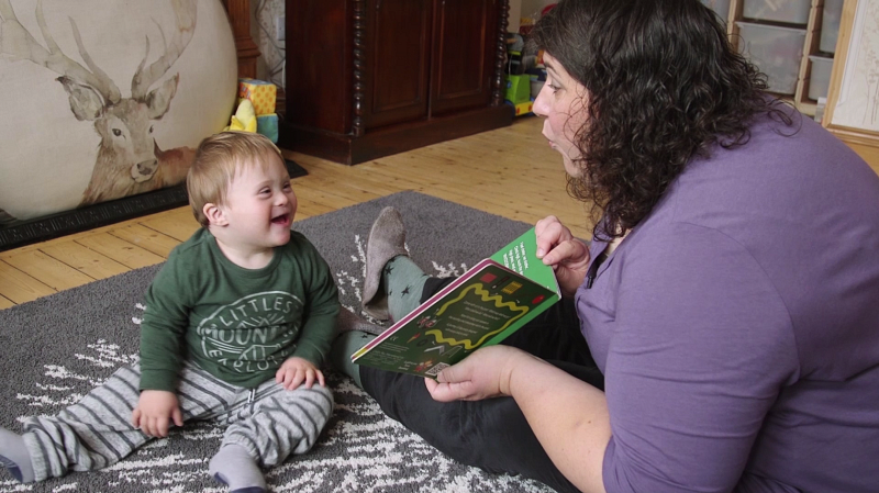 A woman reading a picture book with a toddler