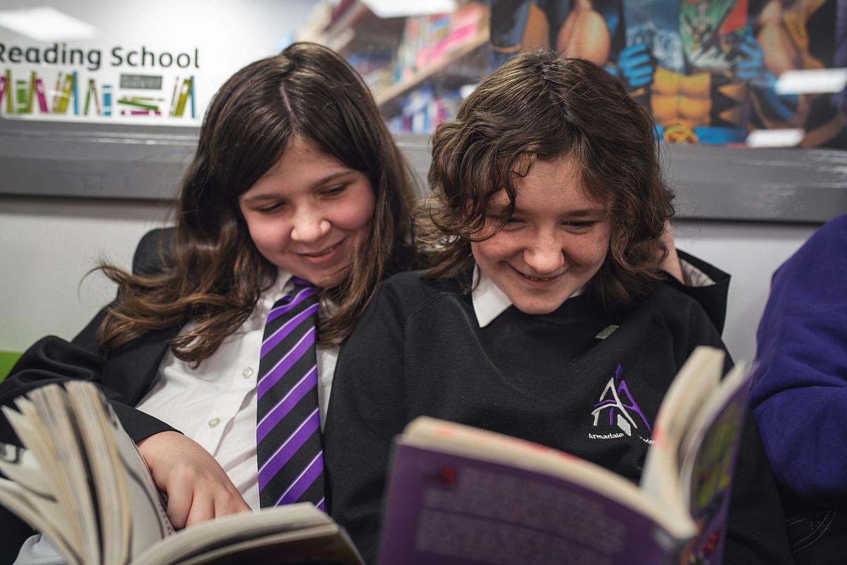 Two children in school uniforms read side by side